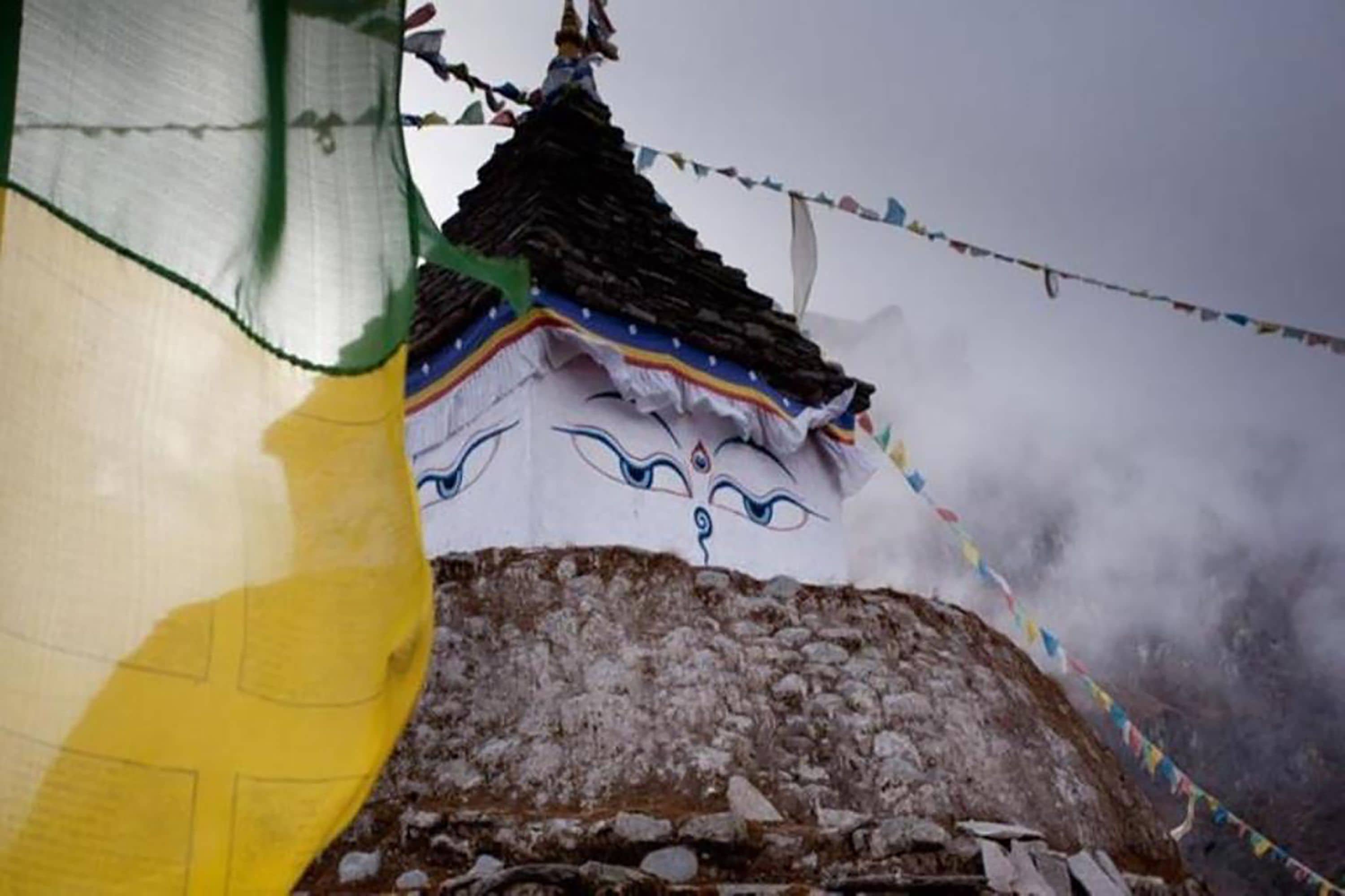 A traditional building with a steep, dark roof and colorful prayer flags.