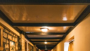 A hallway with wooden walls, a stone accent wall, and a patterned rug on the floor. - Mountain Lodges of Nepal - Namche (Namche Bazar)