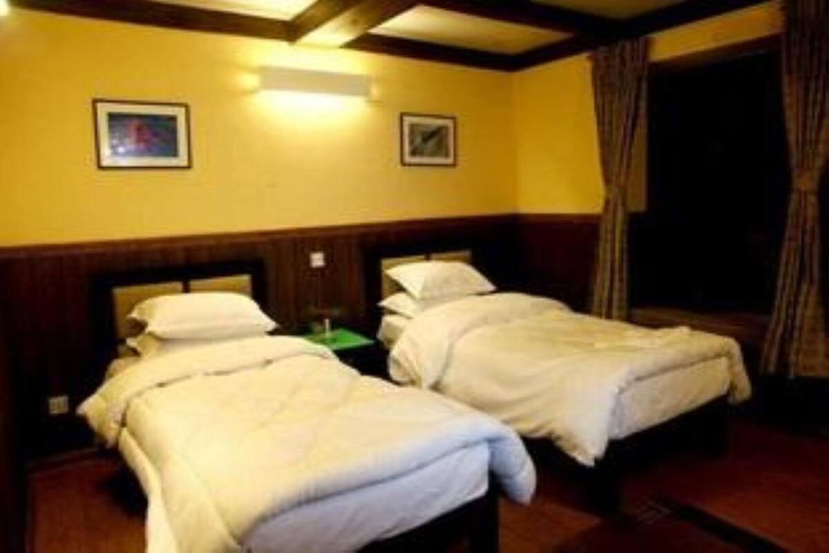 Een hotelkamer met twee eenpersoonsbedden, houten hoofdborden en een groot raam met gordijnen.