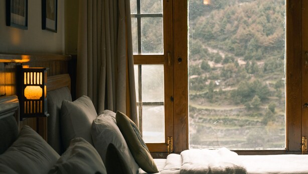 A bedroom with a large window, a bed, a bedside table, and a lamp. - Mountain Lodges of Nepal - Namche (Namche Bazar)