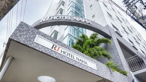 L’entrée de l’hôtel RJ Naha se distingue par une arche ornée de carreaux et une enseigne placée au-dessus.