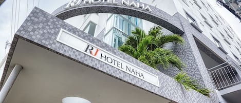La entrada del Hotel RJ Naha, con un arcoado de azulejos y un letrero encima.
