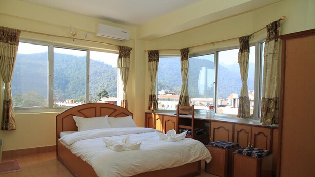 A hotel room with a large bed, a desk, and a view of mountains.