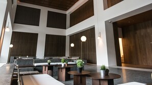 Eine geräumige Lobby mit hohen Decken, Holzvertäfelung und modernen Sitzgruppen.