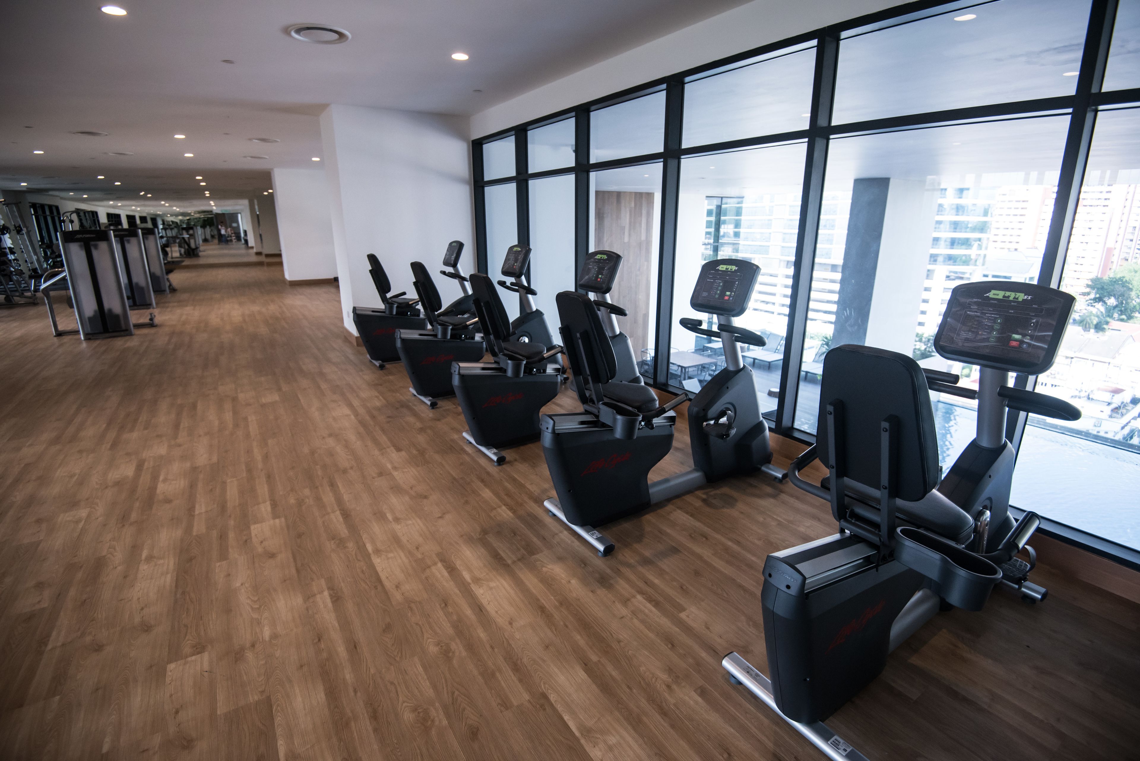 Un gimnasio con equipo de ejercicio y amplias ventanas.