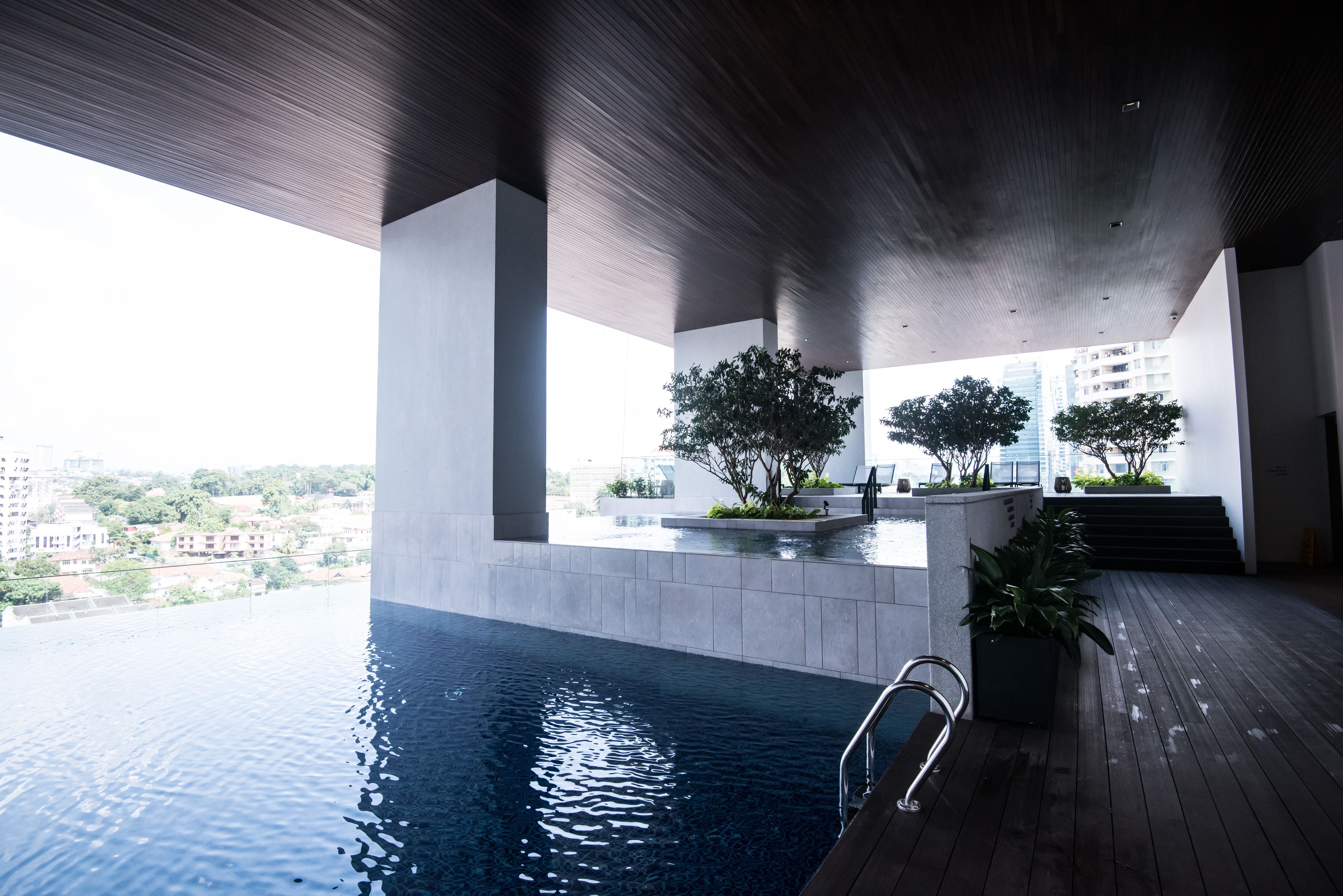 An indoor swimming pool with a view of the cityscape, surrounded by modern architecture and greenery.