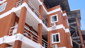Un edificio de varios pisos con paredes exteriores de ladrillo y blanco, balcones con barandillas y unidades de aire acondicionado.