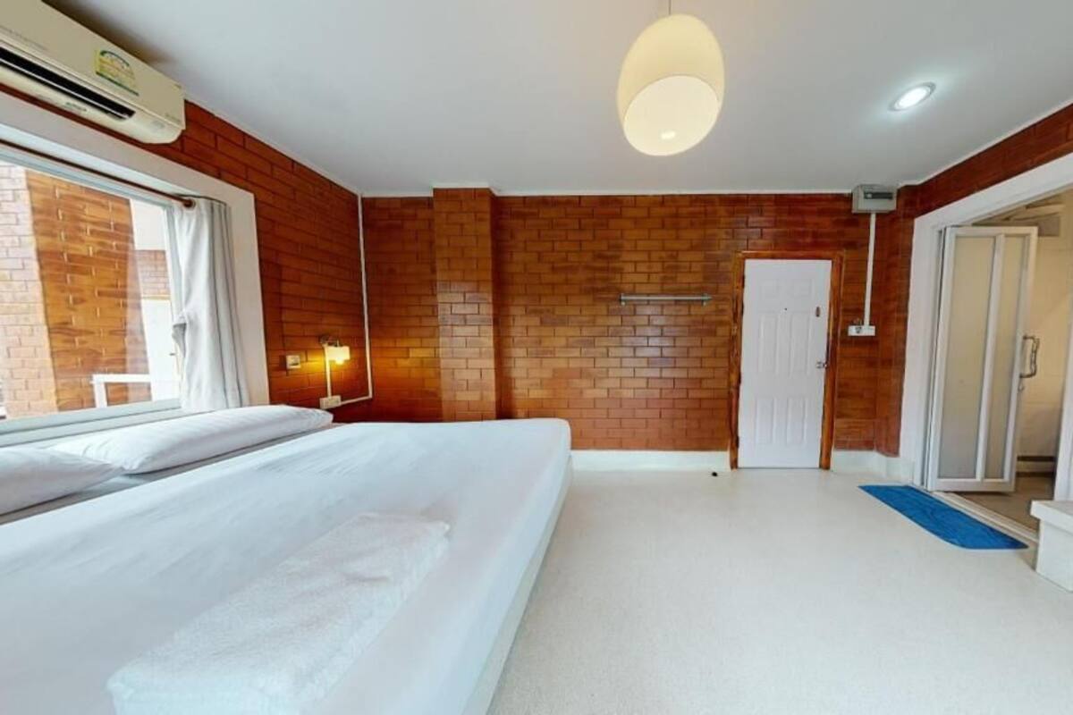 A hotel room with a bed, a desk, a mirror, a door, and a window.