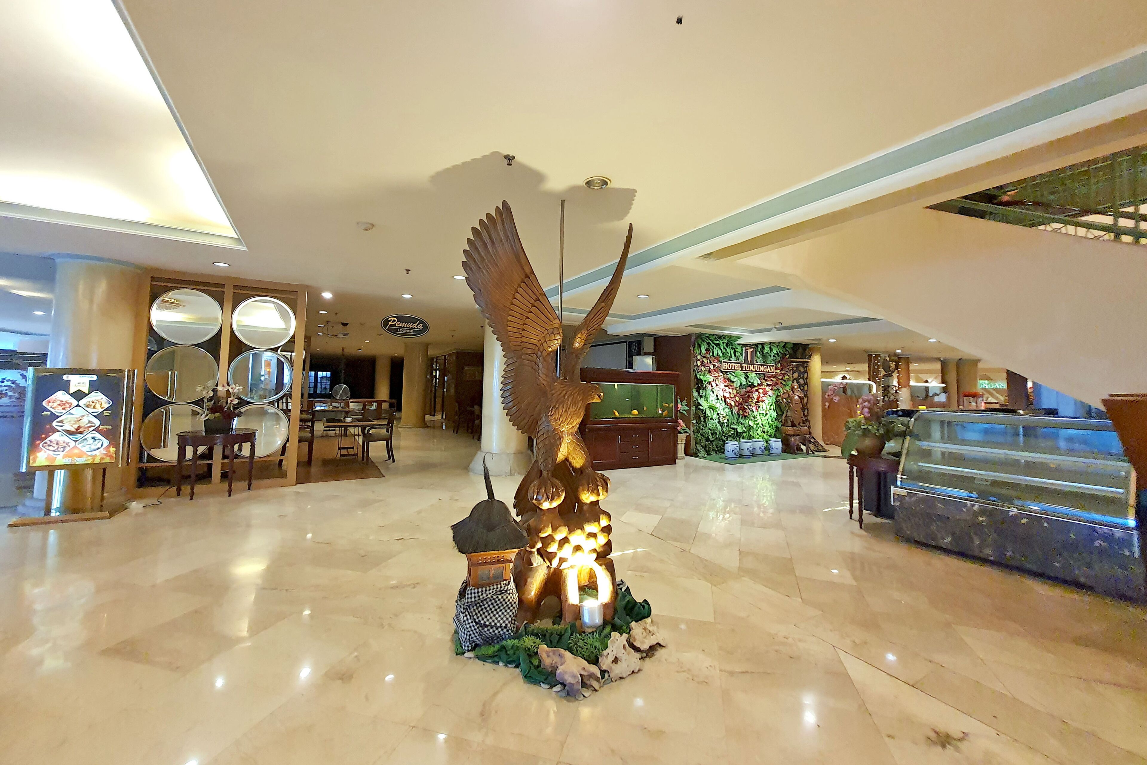 A lobby with a large golden eagle sculpture, a reception desk, and a fish tank.