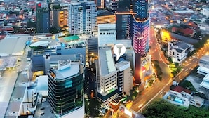 A modern urban area with high-rise buildings, a prominent curved structure, and a busy street with vehicles. - Tunjungan Hotel (Surabaya)