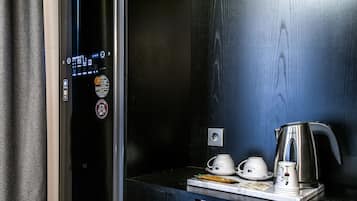 A modern elevator with a digital display, a coffee station with a kettle, cups, and a small table with a notebook and pen.
