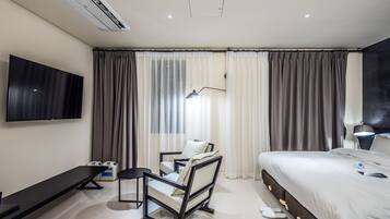 A modern hotel room with a large bed, a desk with a chair, a flat-screen TV, and a window with curtains.