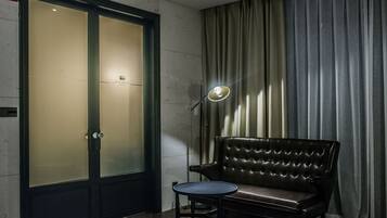 A room with a large frosted glass door, a leather sofa, a small round table, and a floor lamp.