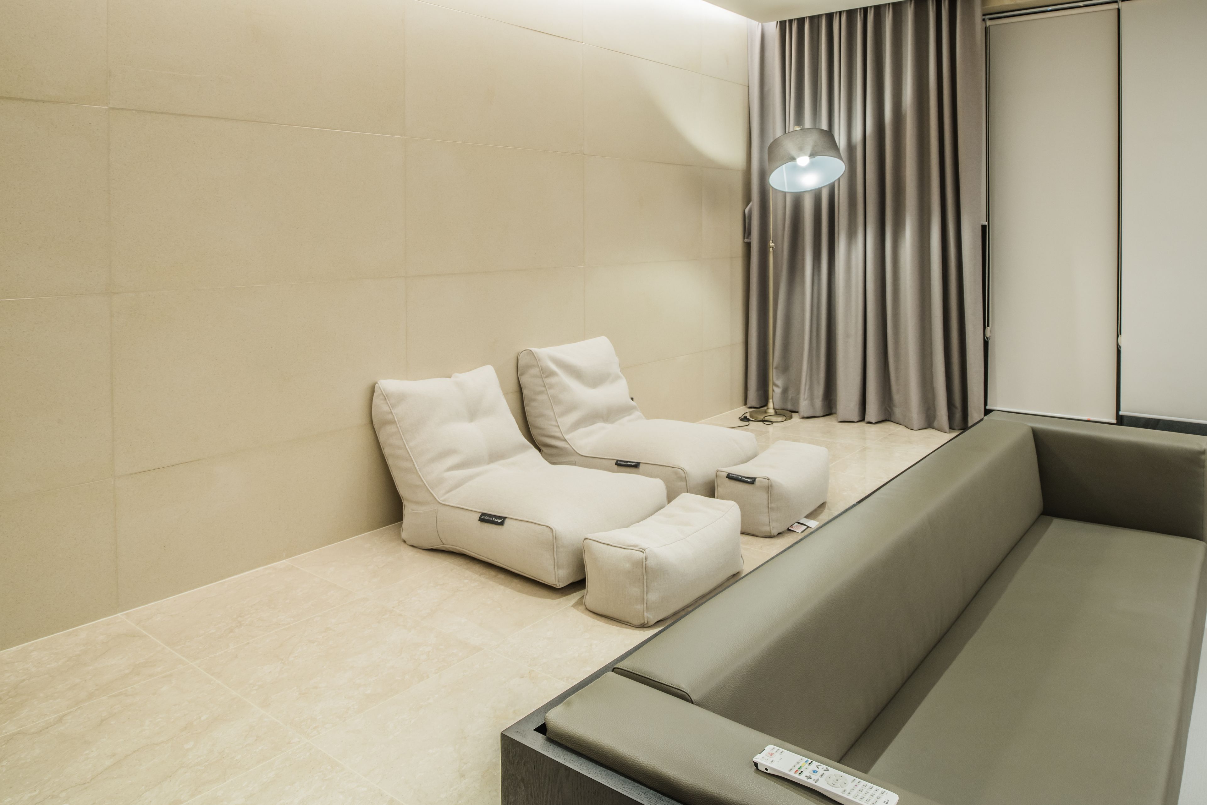 A modern room with a sofa, a massage chair, a remote control, and a lamp.
