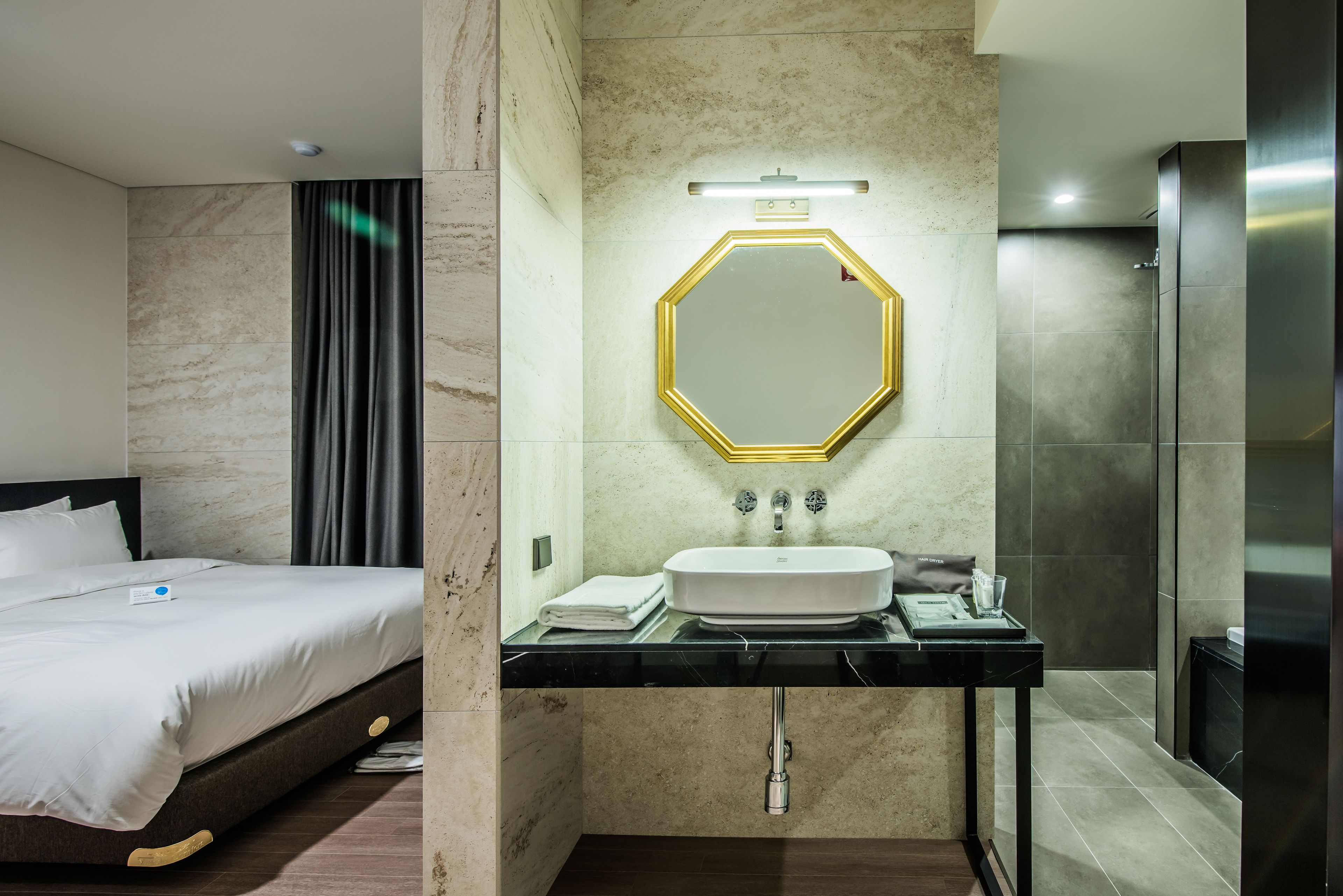Una habitación de hotel con cama, baño con lavamanos y ducha.