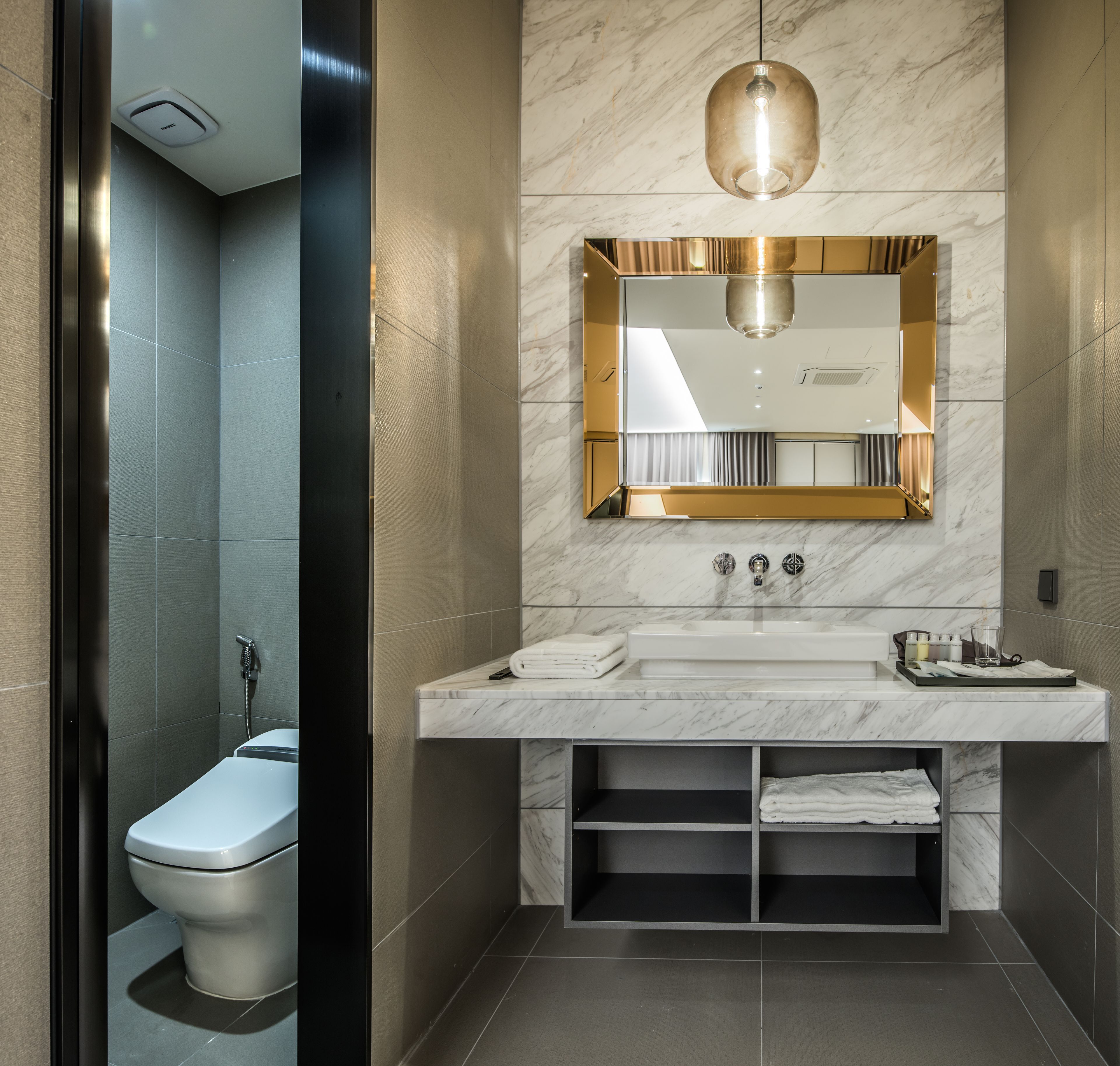 A modern bathroom with a marble vanity, a toilet, and a shower.