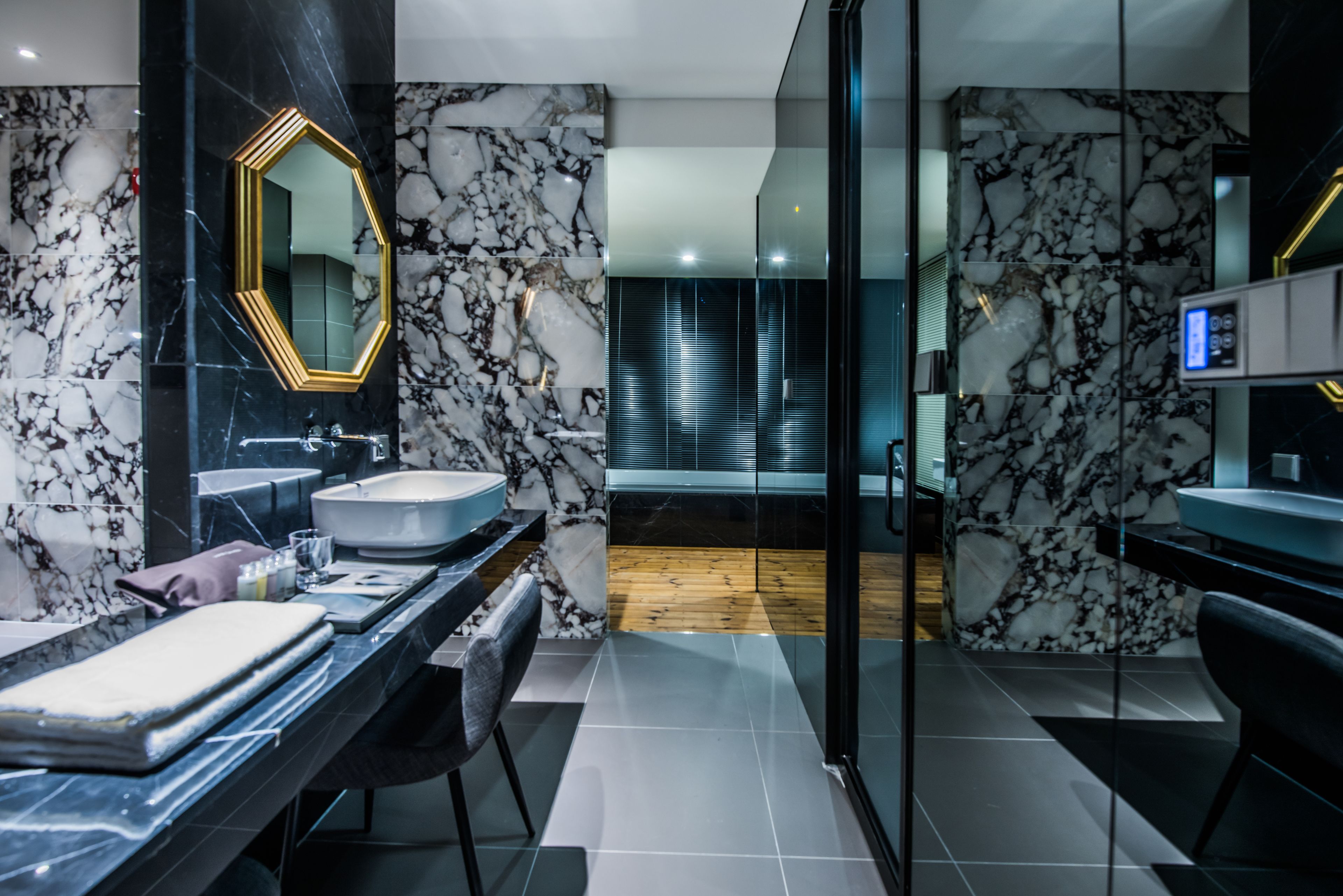 Ein modernes Badezimmer mit Marmorfliesenspiegel, einem großen Spiegel und einer Badewanne.
