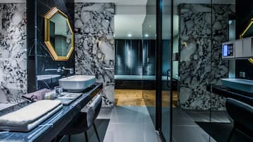 Ein modernes Badezimmer mit Marmorfliesenspiegel, einem großen Spiegel und einer Badewanne.