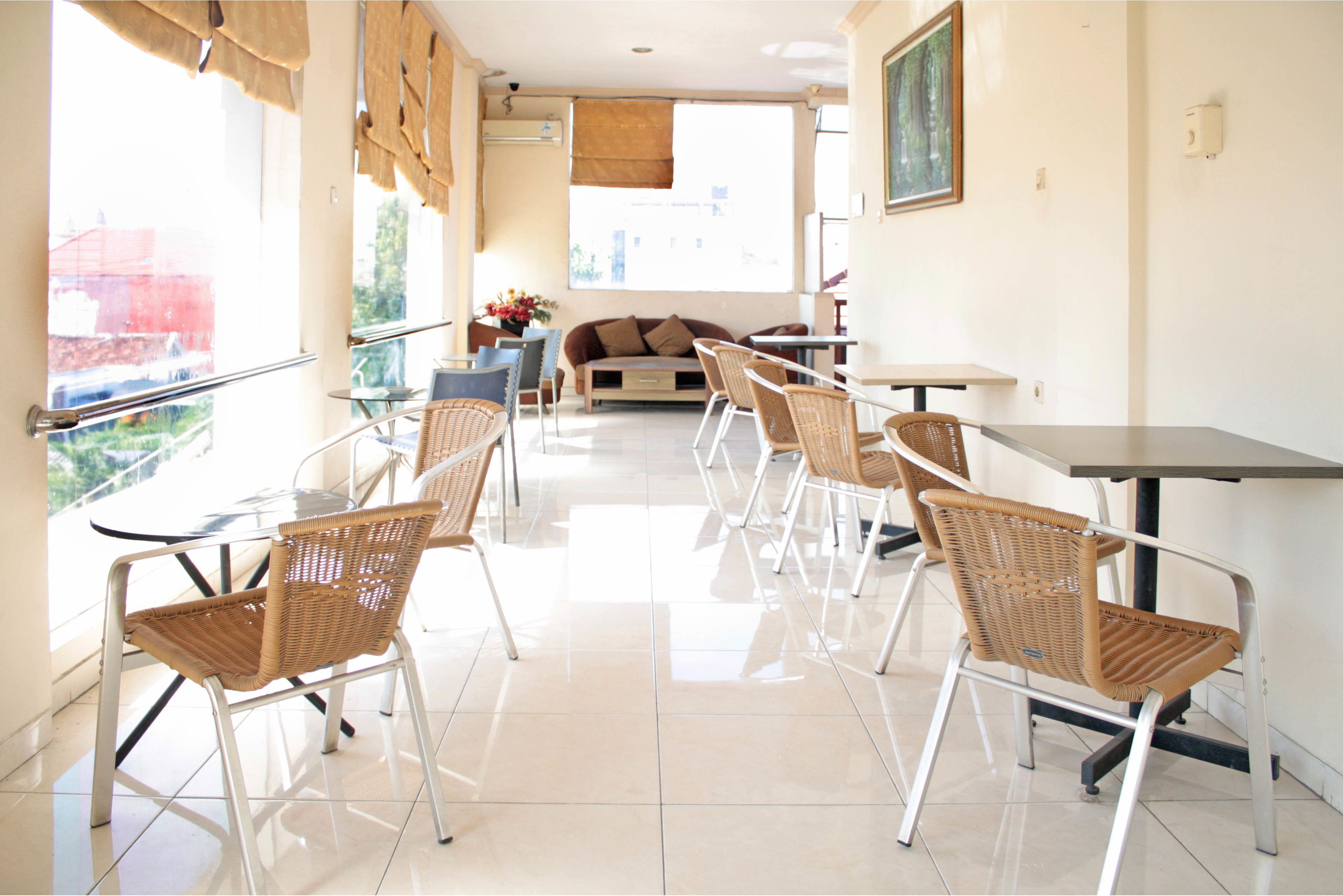 A bright, modern room with a sofa, dining table, and wicker chairs.