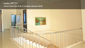 Et moderne interiør med en buet trappe, et maleri af et tropisk landskab og et rent, minimalistisk design.