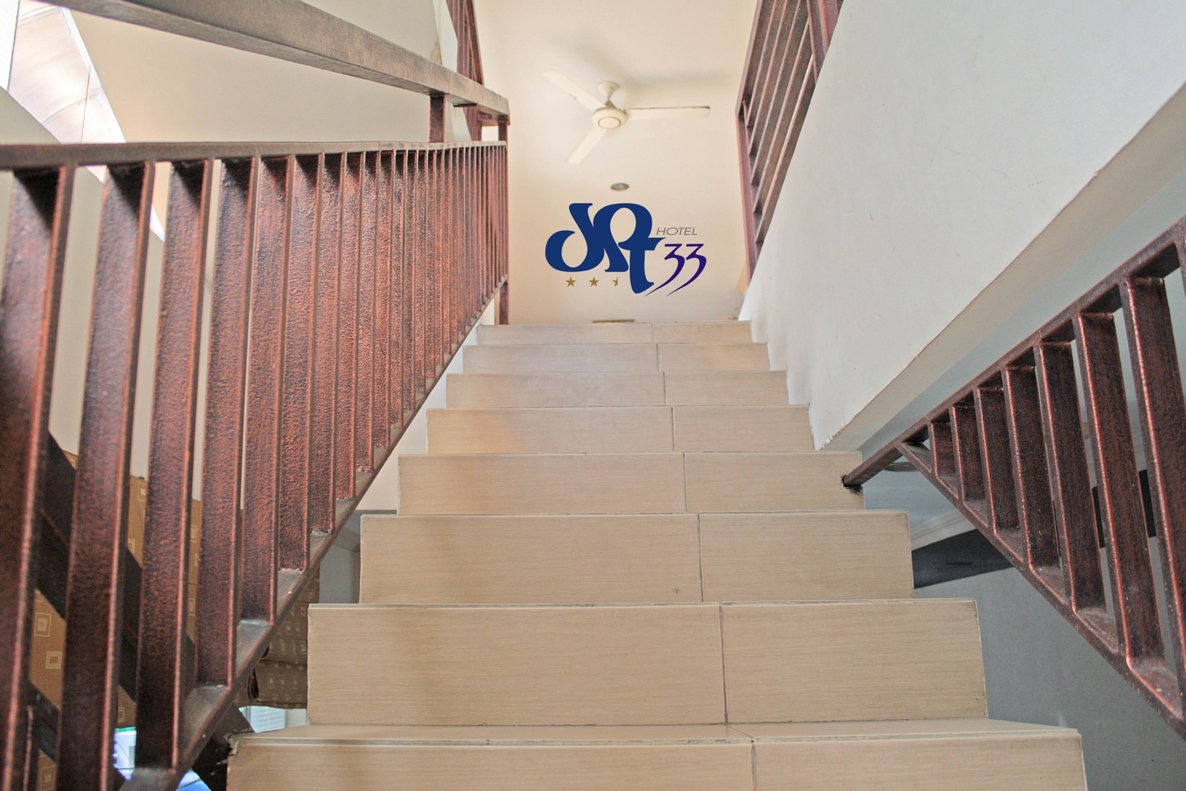 A staircase with wooden steps and metal railings, leading to a room with a ceiling fan and a wall with a logo and stars.