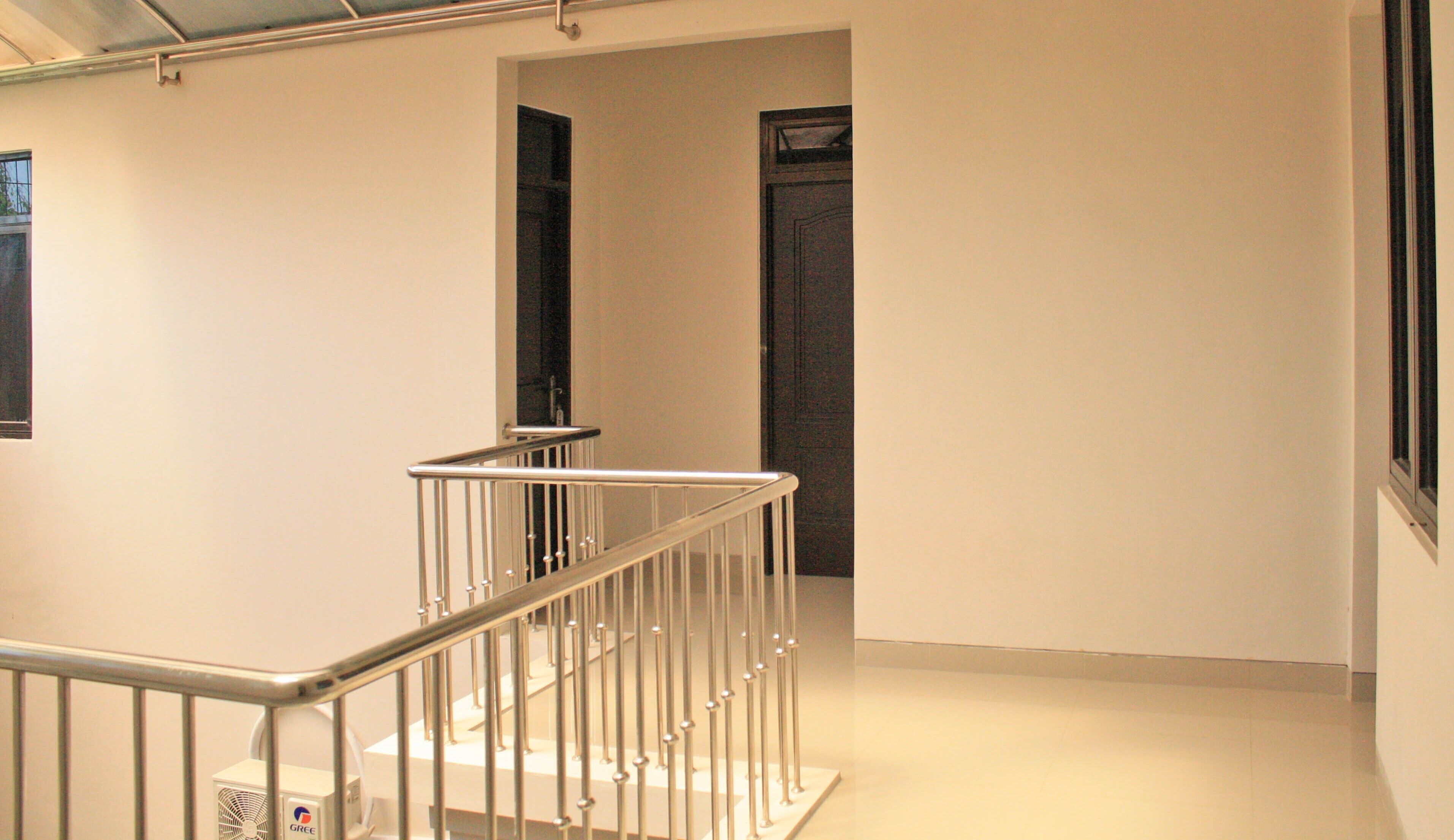 En stilren, modern hall med ett metallräcke och en dörr längst in.
