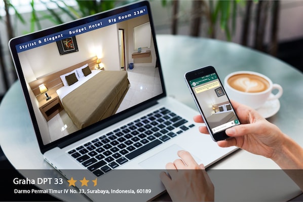 A laptop displaying a room with a bed, bedside table, and a mirror. A smartphone shows a booking interface.