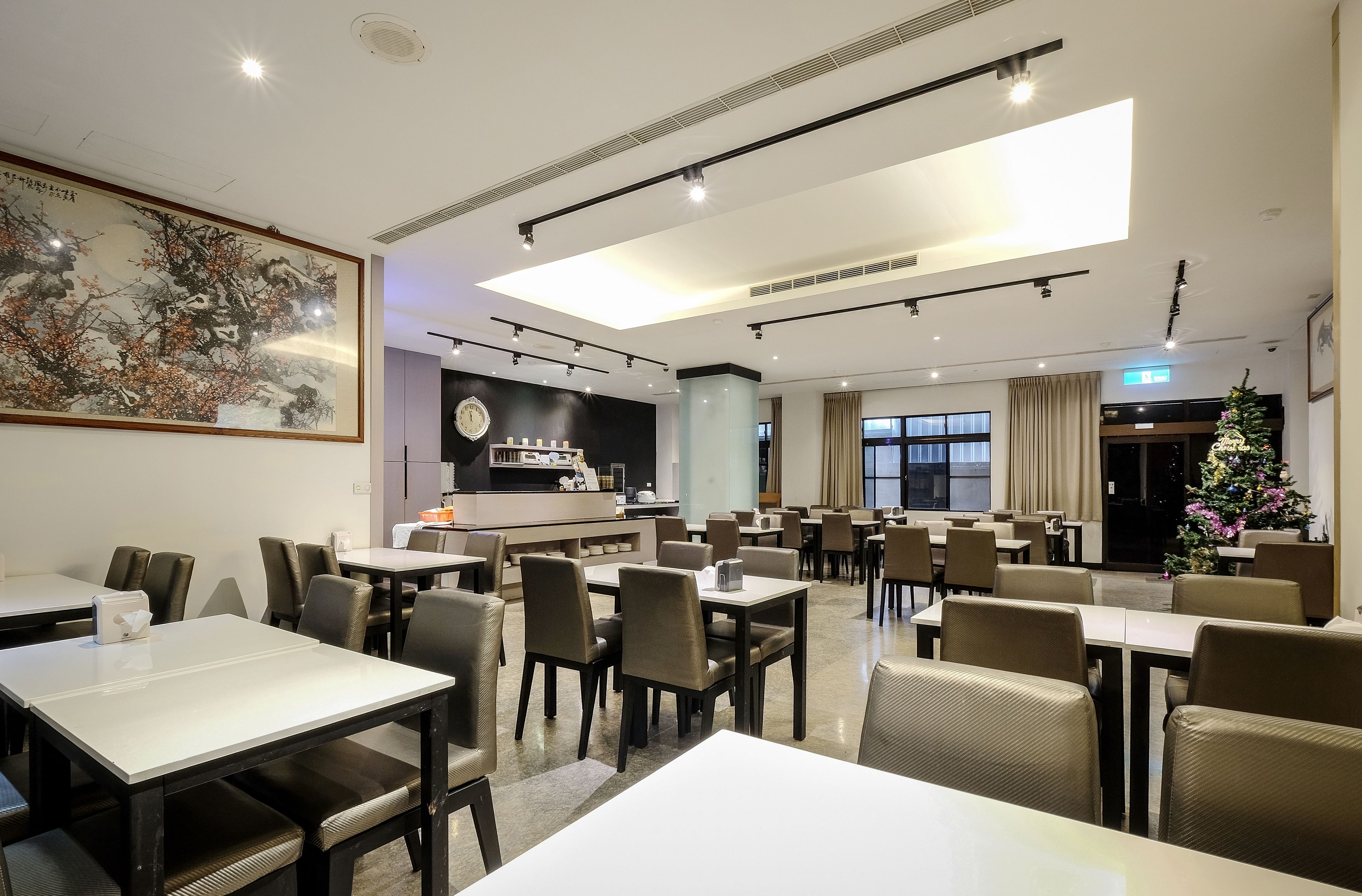 A hotel dining area with tables and chairs, a bar, and a Christmas tree.
