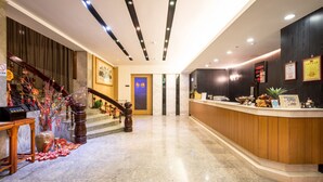 A hotel lobby with a reception desk, a staircase, and a wall-mounted digital display. - Country Garden Hotel (Chiayi City)