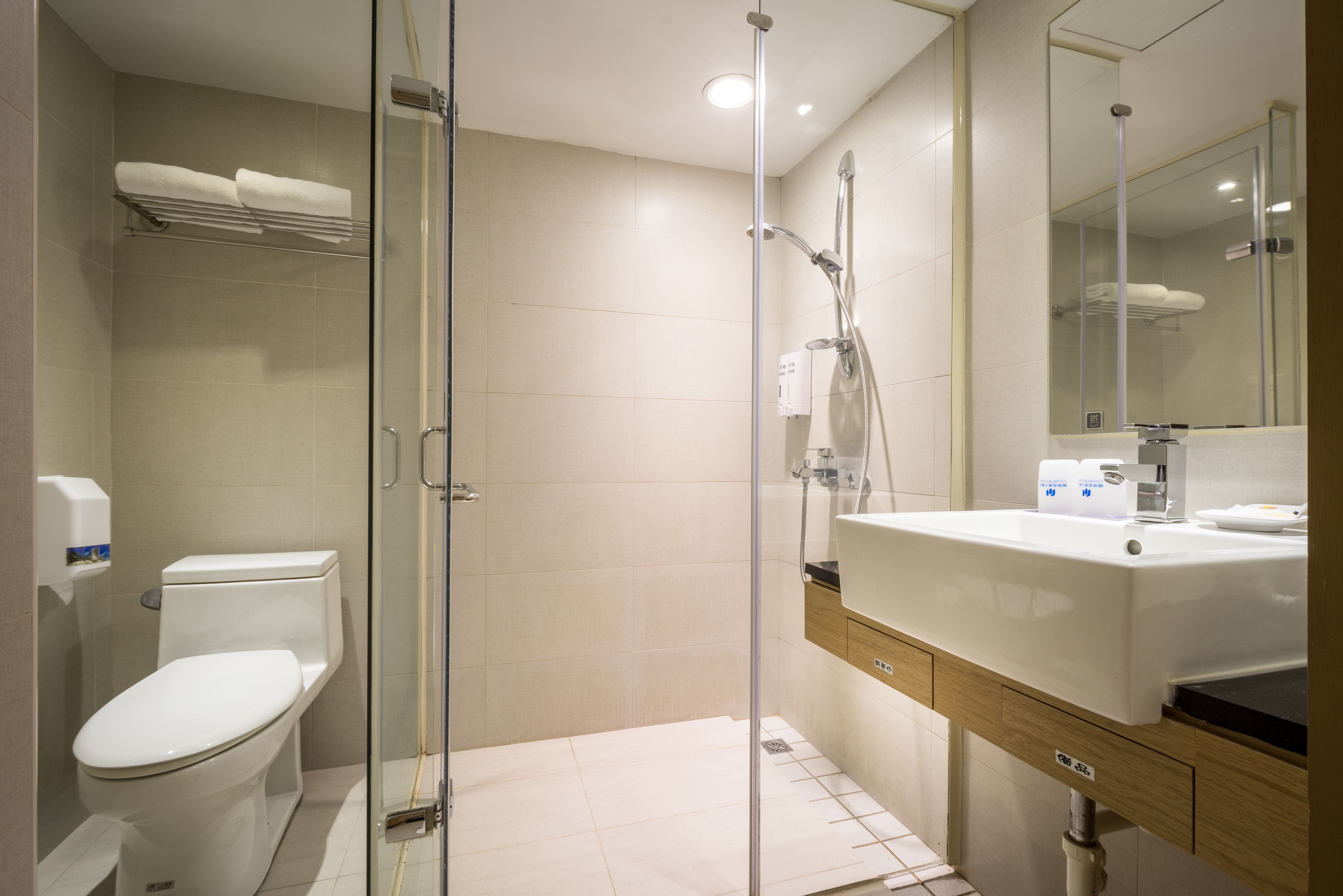 Une salle de bain moderne avec une douche à parois de verre, des toilettes blanches et un lavabo avec un miroir au-dessus.