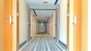 A hotel hallway with striped carpet, wooden doors, and a ceiling with recessed lighting. - Country Garden Hotel (Chiayi City)