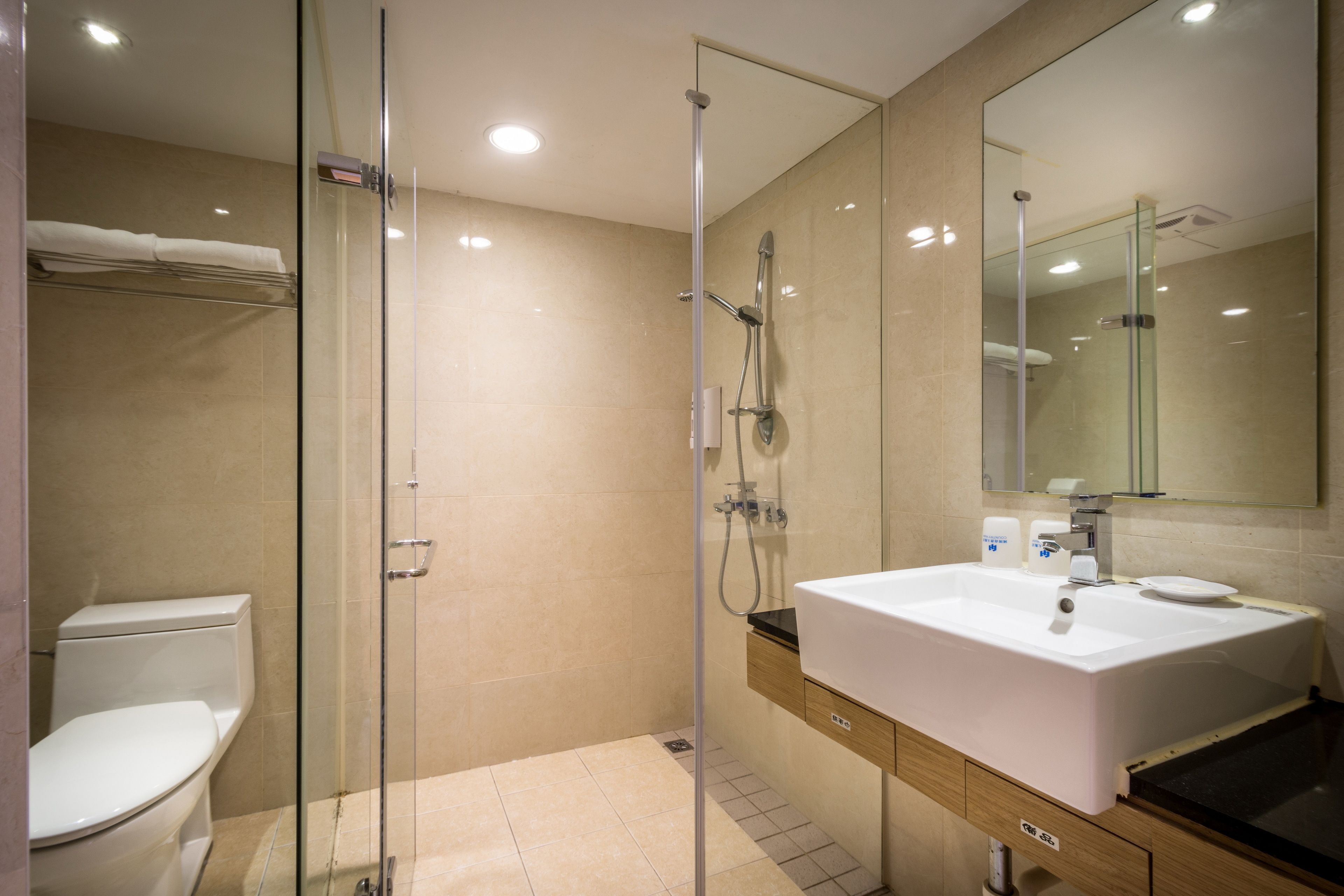 A modern bathroom with a glass-enclosed shower, a white sink, and a toilet.