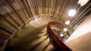 A spiral staircase with a wooden handrail and a light fixture at the top. - Country Garden Hotel (Chiayi City)