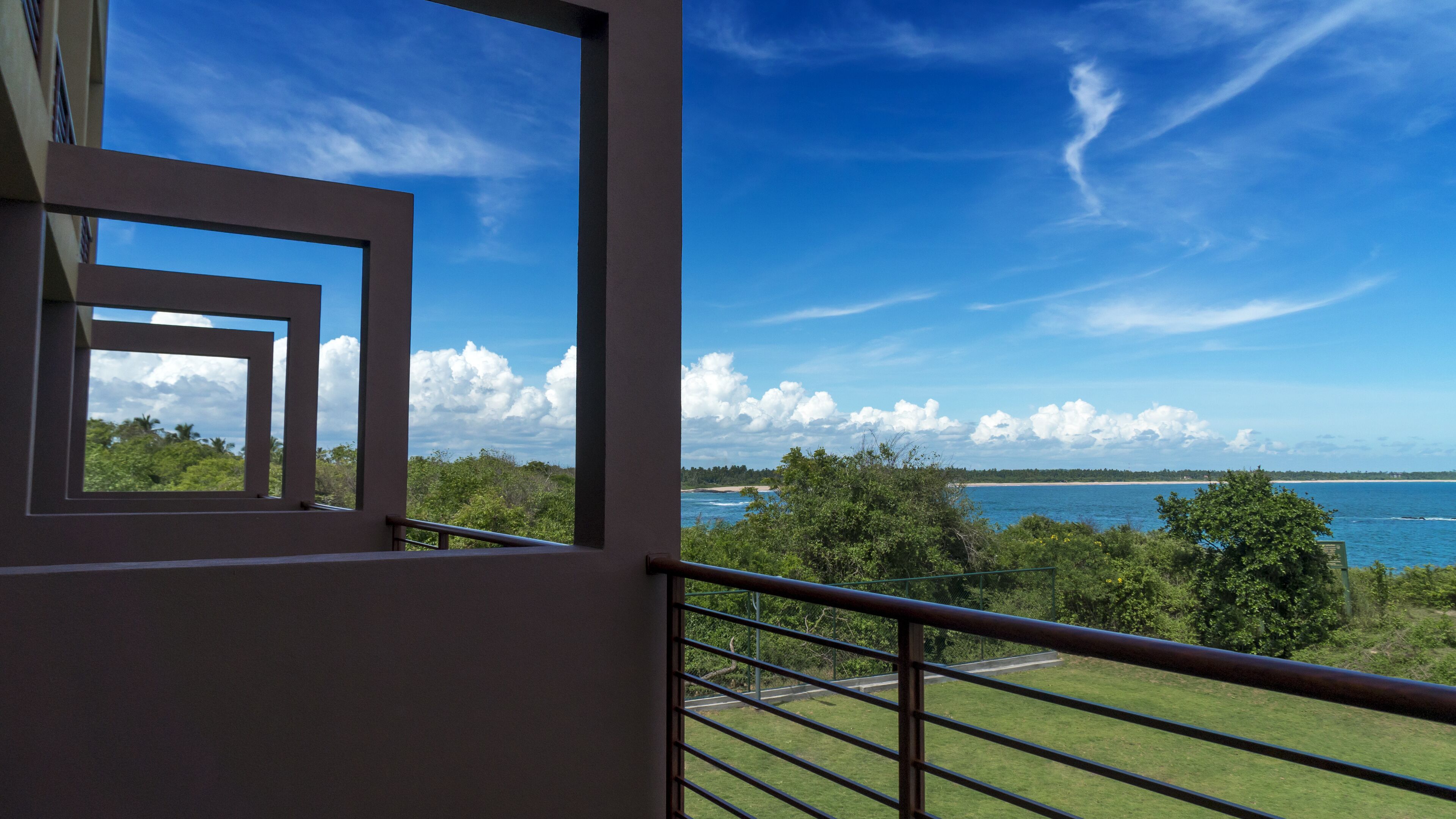 A balcony with a view of the sea and a distant beach.