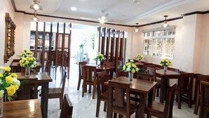 Uma sala de jantar com mesas e cadeiras de madeira, ventiladores de teto e luminárias decorativas.