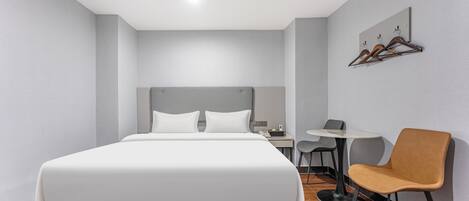 Una habitación de hotel moderna con una cama grande, un escritorio con una silla y una mesita.