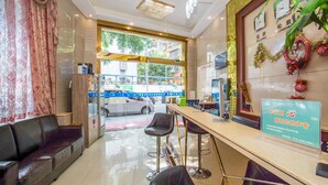A hotel lobby with a reception desk, two bar stools, a sofa, and a large window offering a view of the street outside. - Kaixin Express Hotel (Shenzhen)