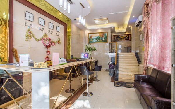 A reception area with a desk, chairs, a staircase, and a painting on the wall. - Kaixin Express Hotel (Shenzhen)