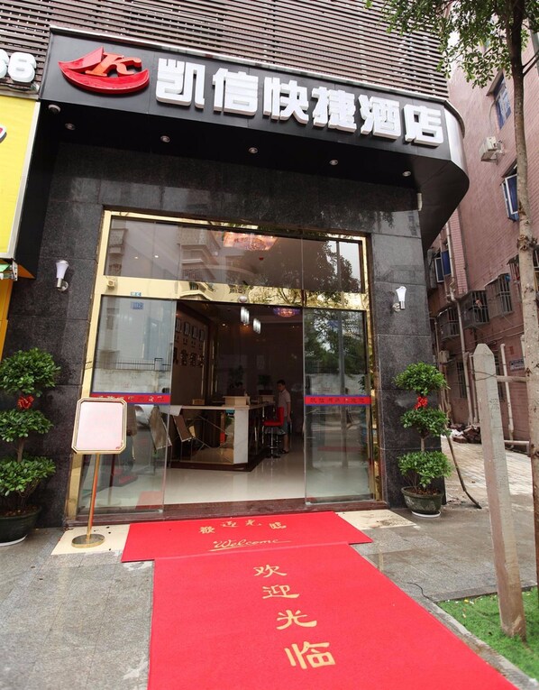 Entrada de hotel con alfombra roja y un cartel con caracteres chinos.