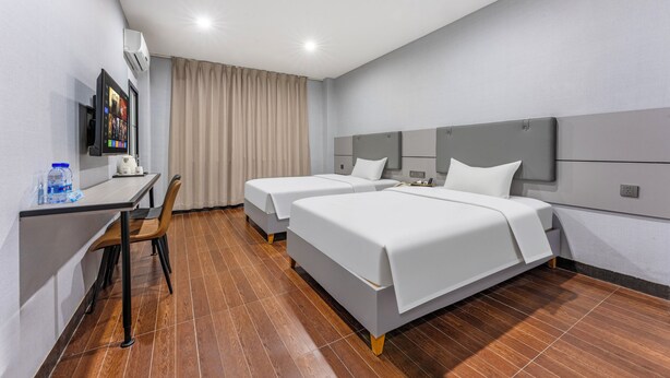 A hotel room with two beds, a desk, a chair, a TV, and an air conditioning unit. - Kaixin Express Hotel (Shenzhen)