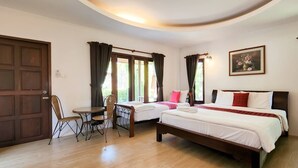 A bedroom with two beds, a dining table with chairs, and a painting on the wall. - Waterside Resort (Pranburi)