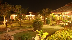 A well-lit resort area with multiple buildings, pathways, and lush greenery. - Waterside Resort (Pranburi)