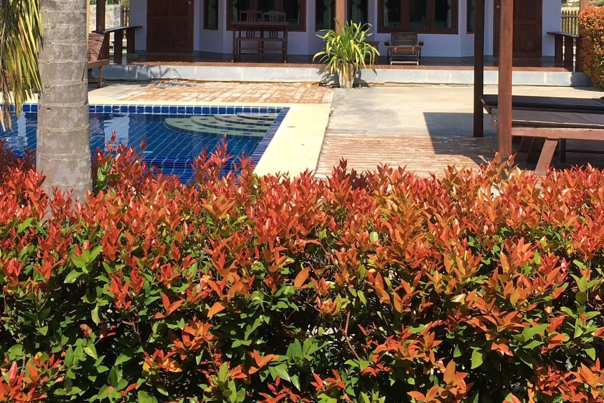 Uma casa com telhado de cerâmica, piscina e área de varanda coberta.