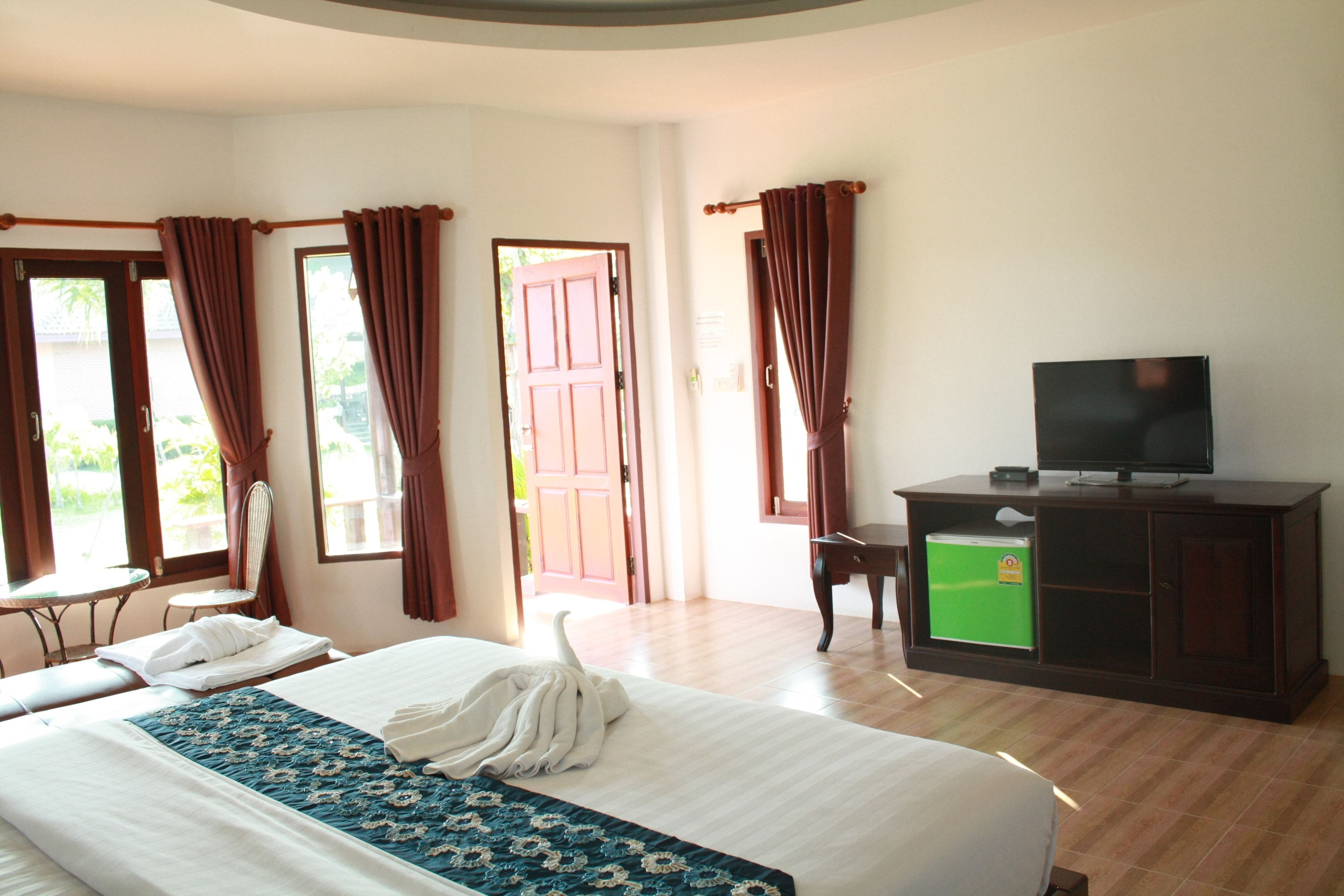 A hotel room with a bed, a television on a cabinet, a desk, and a chair.