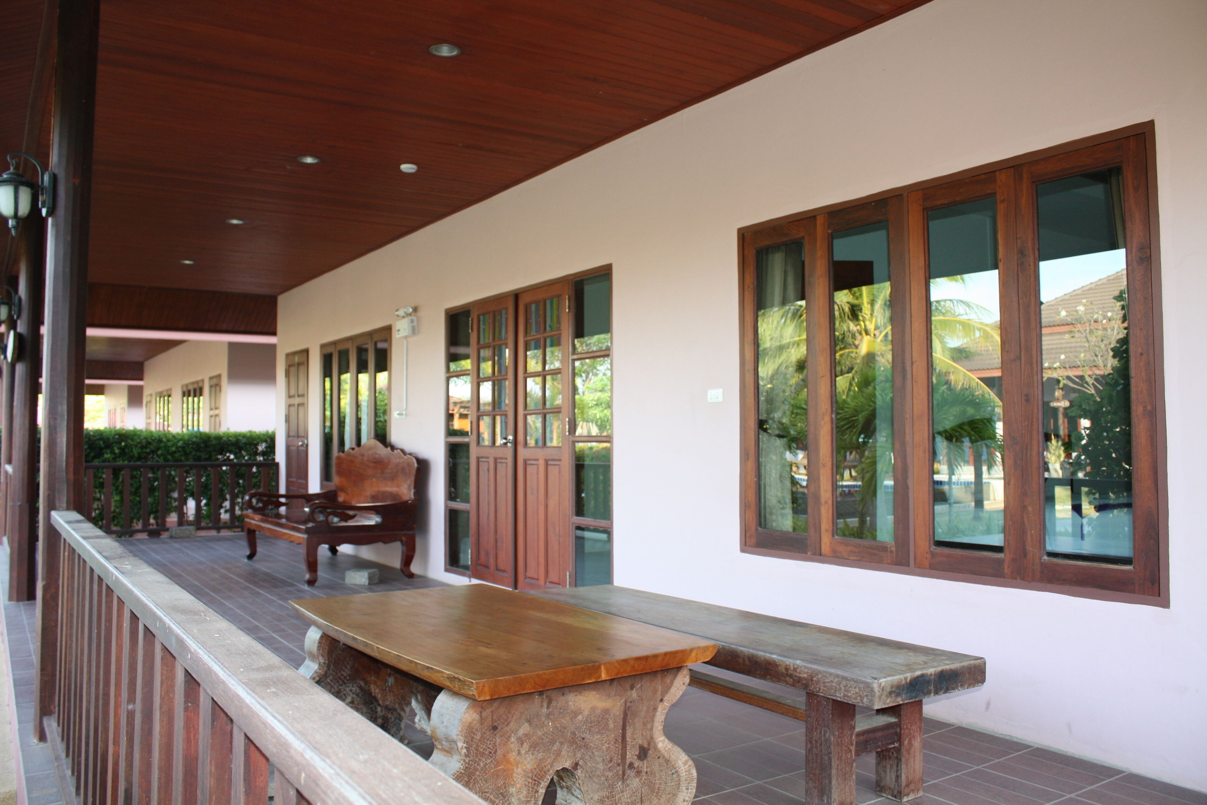 A covered outdoor area with a wooden bench, a table, and a railing.