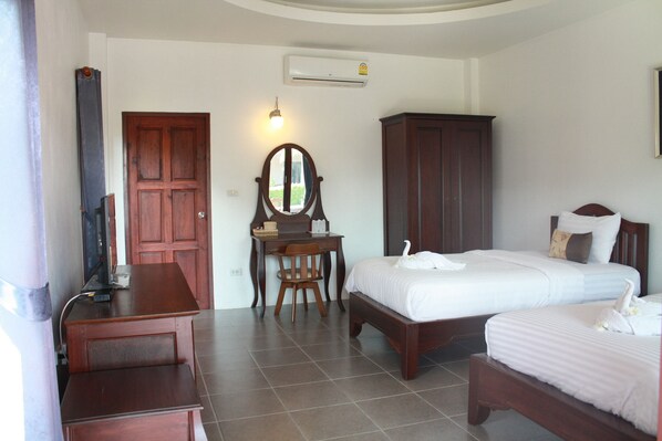 A hotel room with a wooden desk, a chair, a bed with white bedding, a wardrobe, and a mirror.