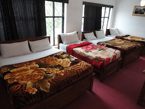 A hotel room with four beds, each with a different floral bedspread. - Sapu's Mountain Breeze (Nuwara Eliya)
