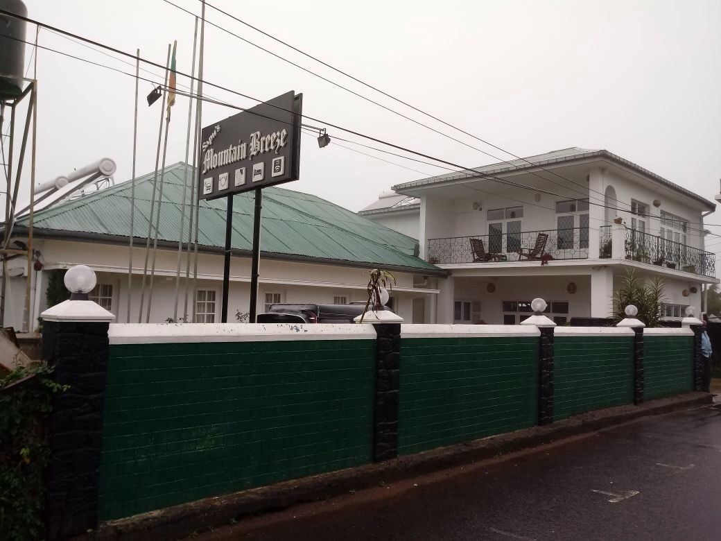 A hotel with a green exterior wall, a signboard, and a balcony.