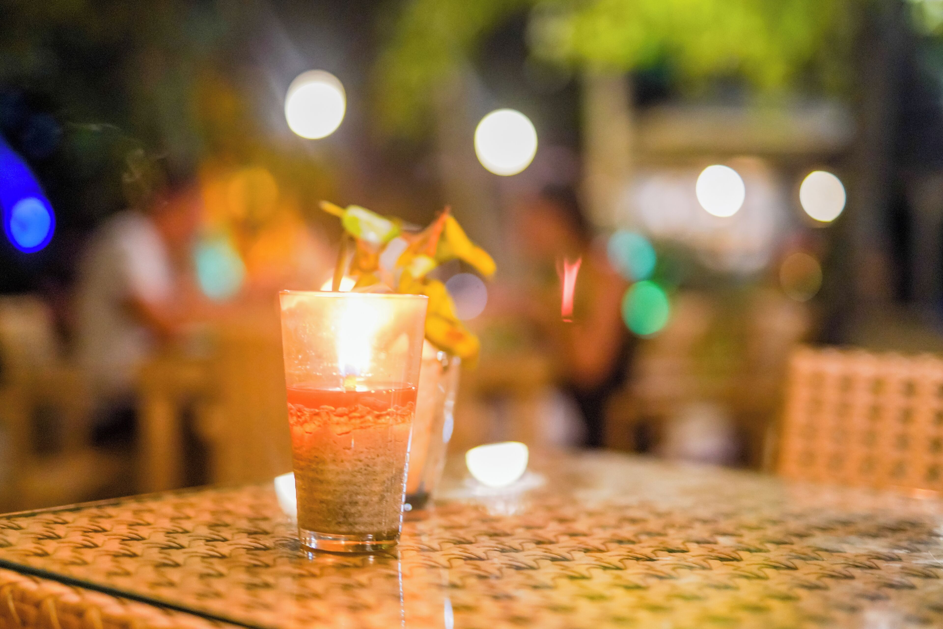 A glass of iced beverage on a table with a blurred background of lights.