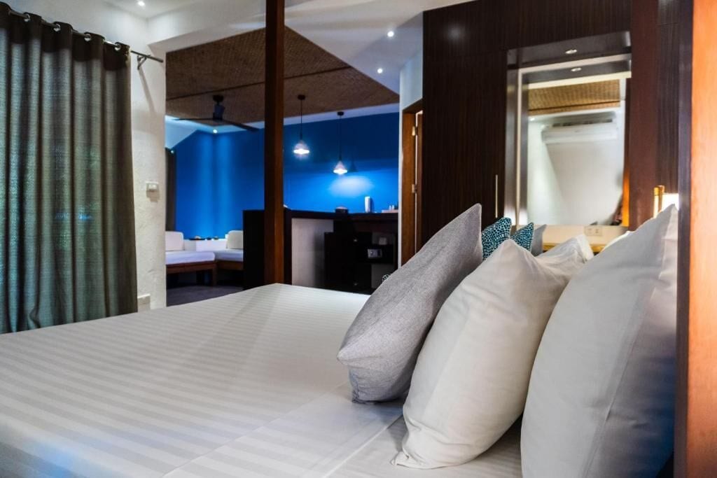 Una habitación de hotel con una cama, almohadas, un escritorio y un baño visible al fondo.